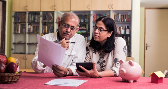 An Indian couple checking their utility bill in the kitchen.